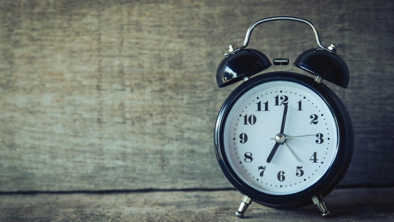 Clock, pen, and notepad on a desk